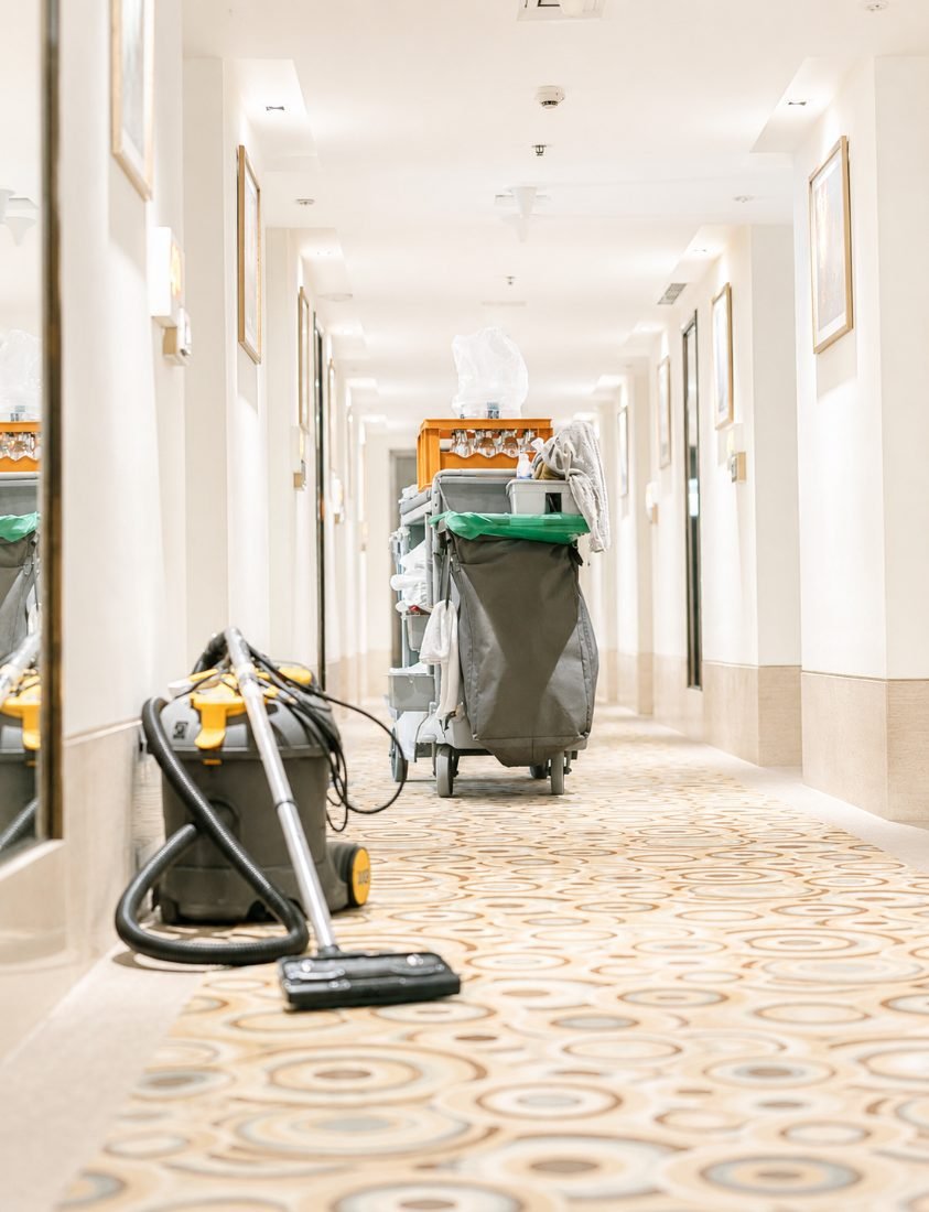 Hotel housekeeping cart and vacuum staged in a hallway between guest turnovers