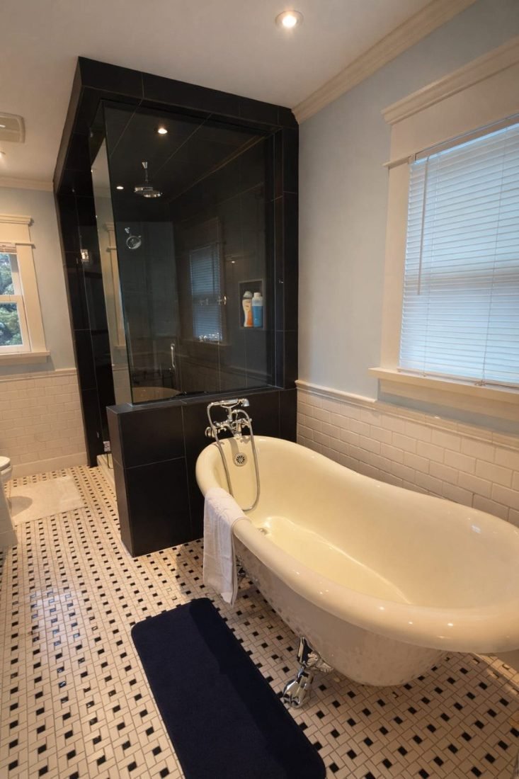A pristine bathroom with a clawfoot soaking tub, glass-enclosed shower and tiled floor